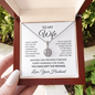 To My Wife necklace in the mahogany gift box surrounded by green foliage