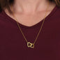 Yellow gold Interlocking Hearts necklace worn with a burgundy top