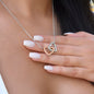 Interlocking Hearts pendant in rose gold and silver held in a hand